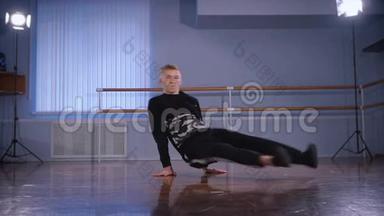 专业的舞蹈演员在舞蹈室的地板上跳着他壮观的舞蹈。 训练有素的舞蹈动作。 青年